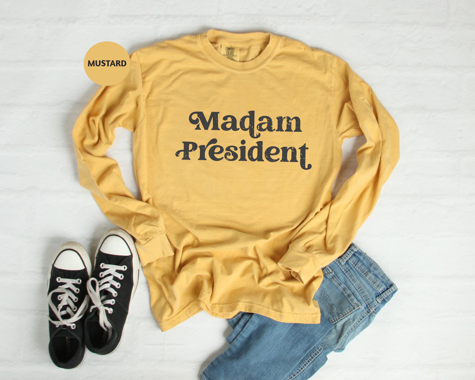 a yellow shirt that says madam president next to a pair of black sneakers