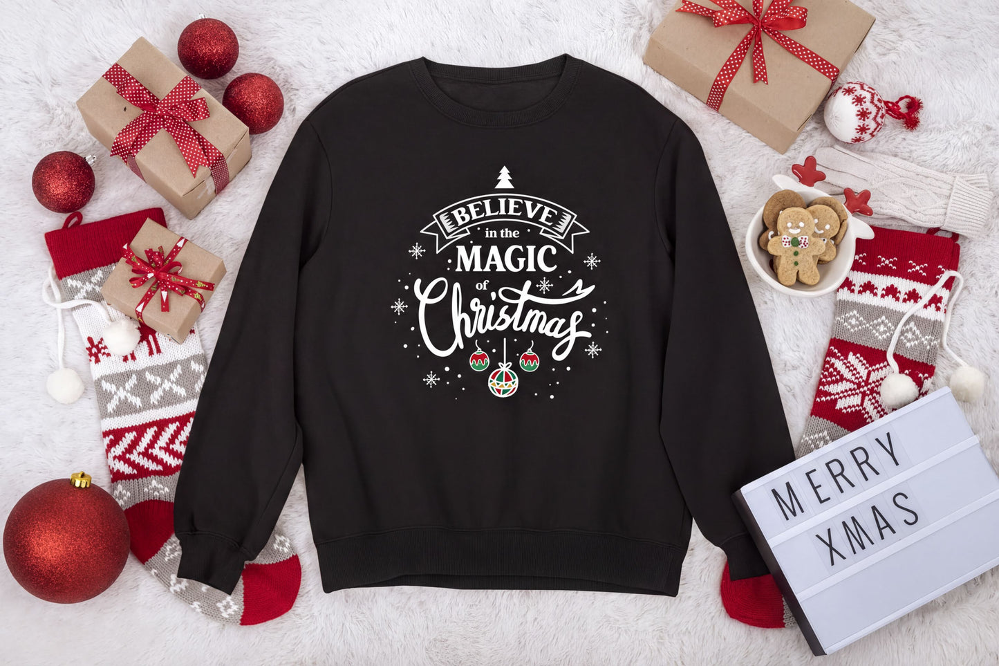 A black sweatshirt with a Christmas-themed design, surrounded by various holiday decorations and gifts, including a sign that says "Merry Xmas".