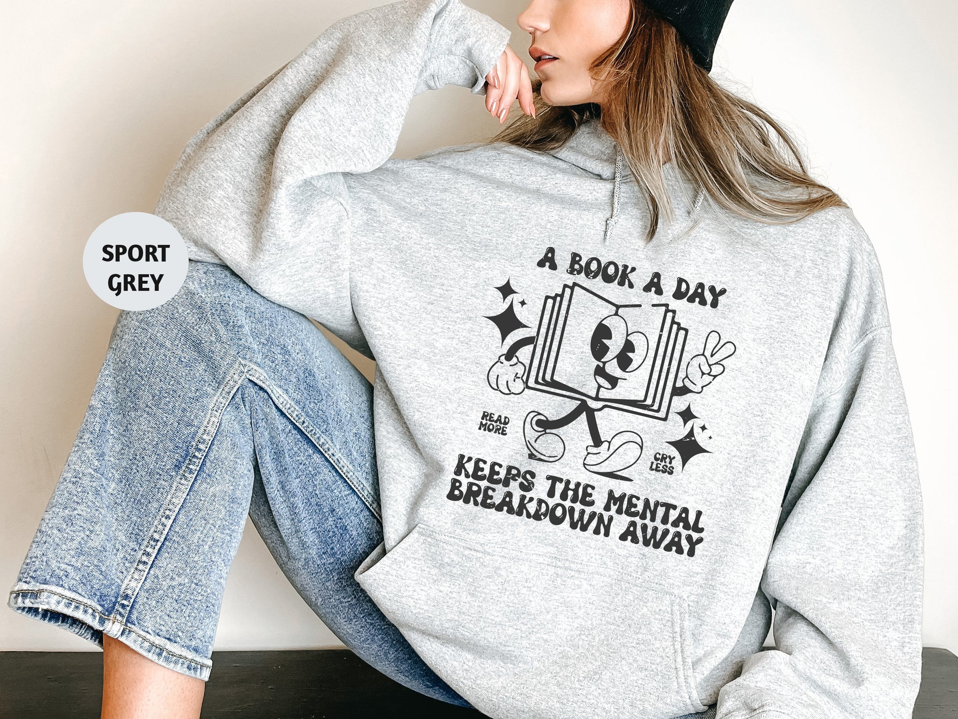 a woman sitting on the floor wearing a book a day hoodie