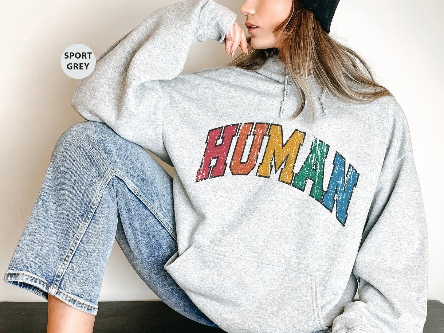 a woman sitting on the ground wearing a sweatshirt with the word human on it