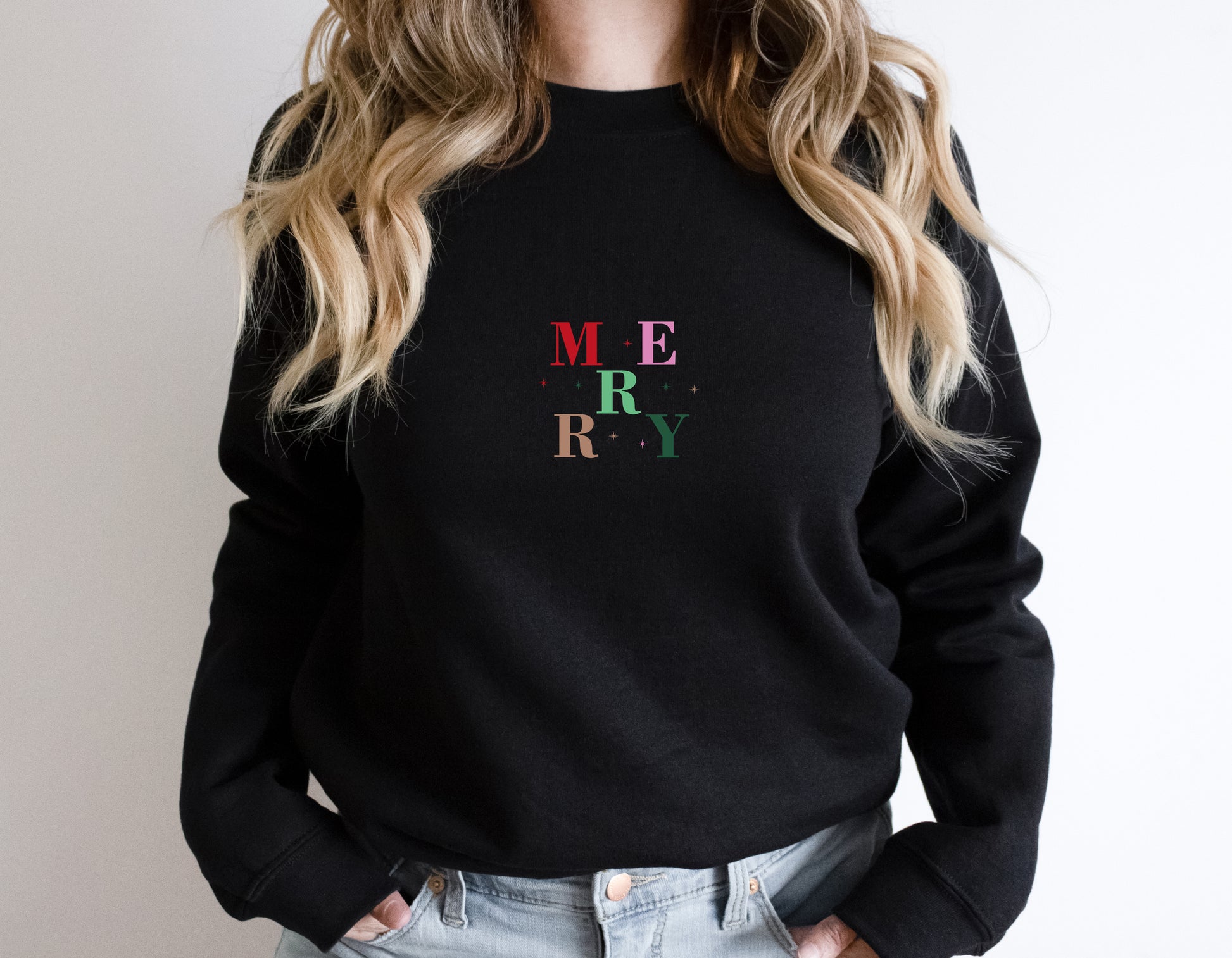A woman wearing a black sweater with the word "MERRY" printed on it.