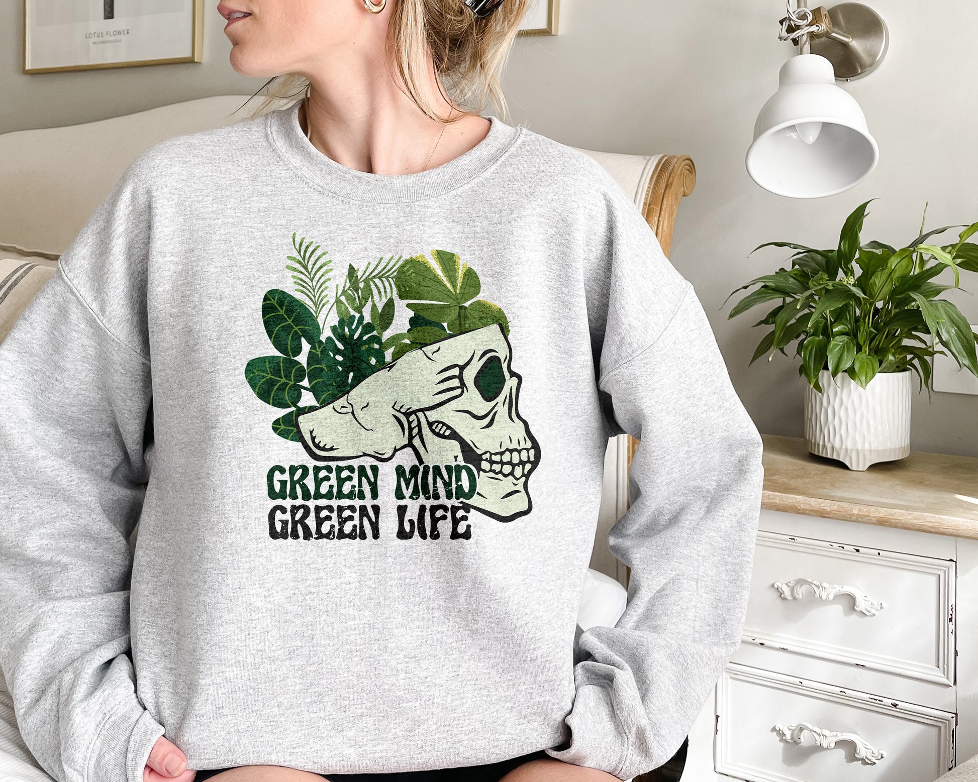 a woman sitting on a couch wearing a green mind sweatshirt