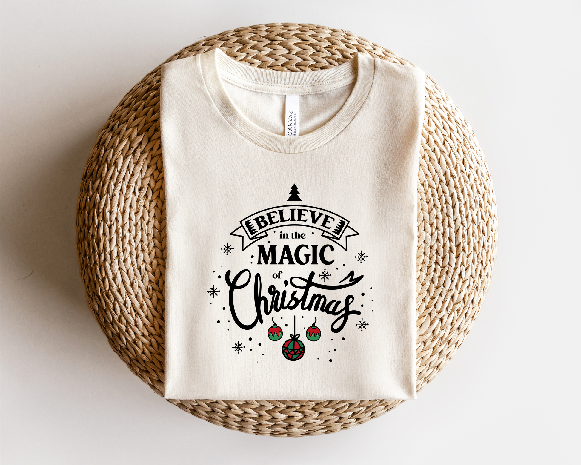 A white t-shirt with a printed design on it, which says "Believe in the Magic of Christmas".