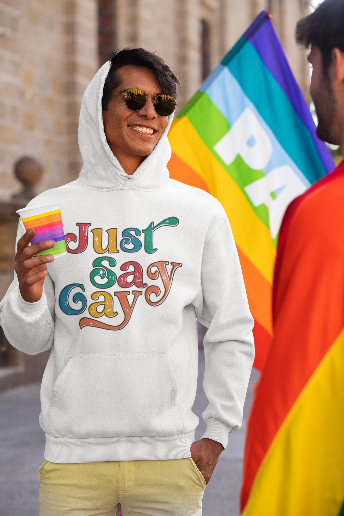 a man in a white hoodie holding a rainbow flag