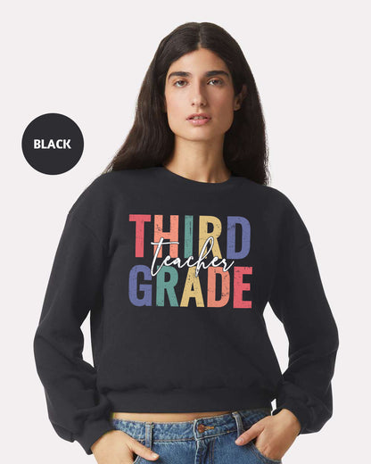 a woman wearing a black sweatshirt that says third grade