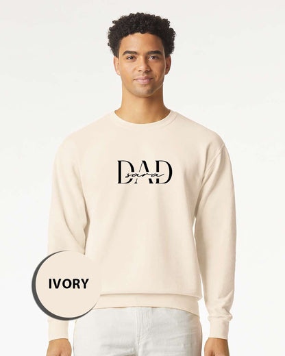 A man wearing a cream-colored sweater with the text "DAD" printed on it.