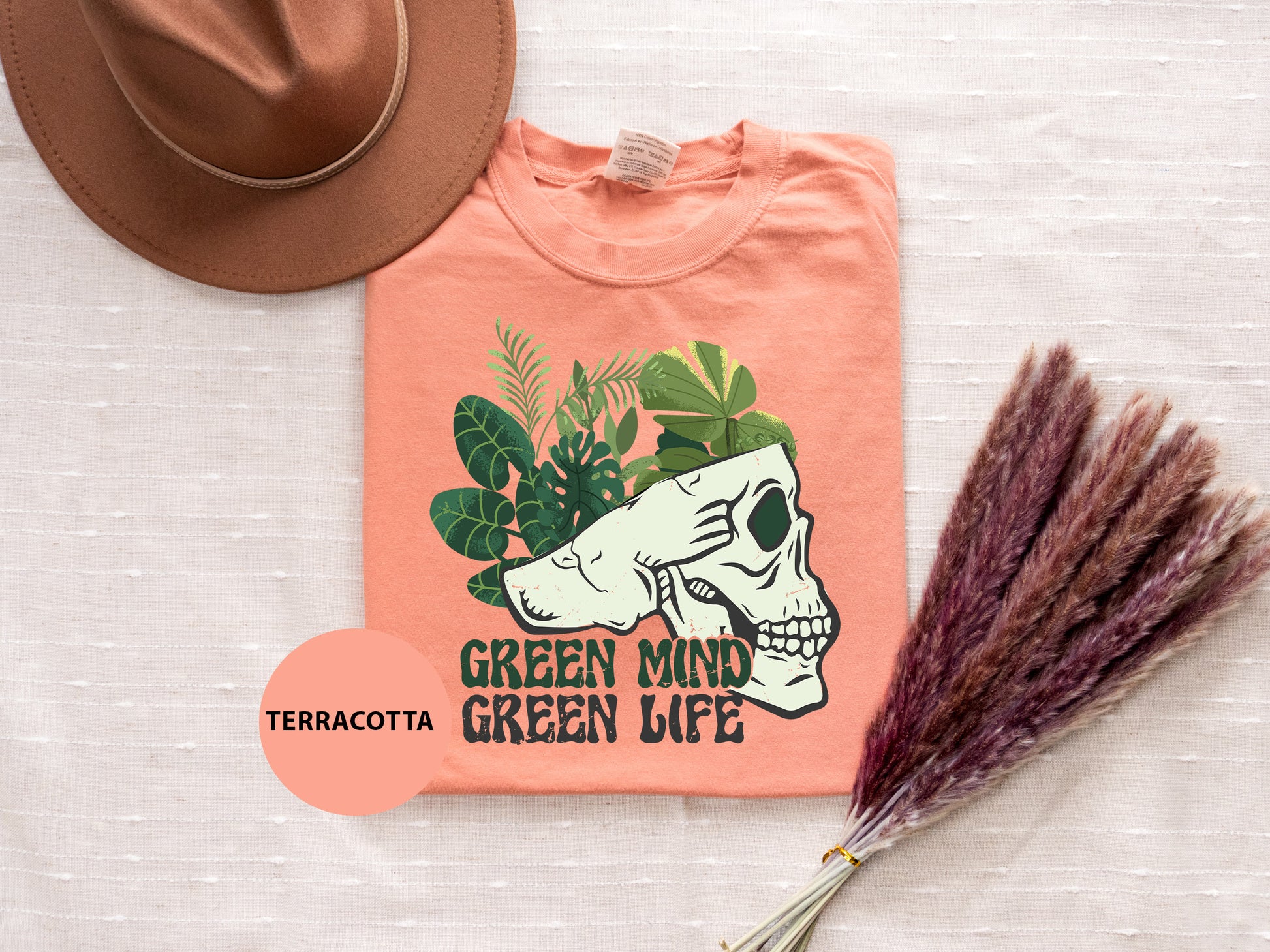 a t - shirt with a skull on it and a hat next to it