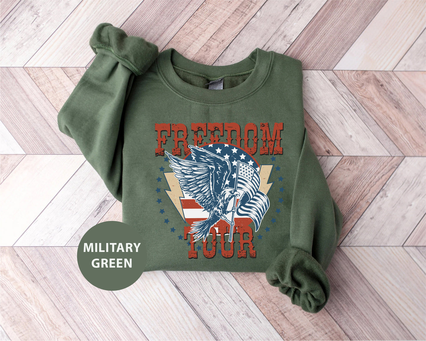 A military green sweatshirt with a graphic design of an eagle and the text "FREEDOM TOUR" printed on it.