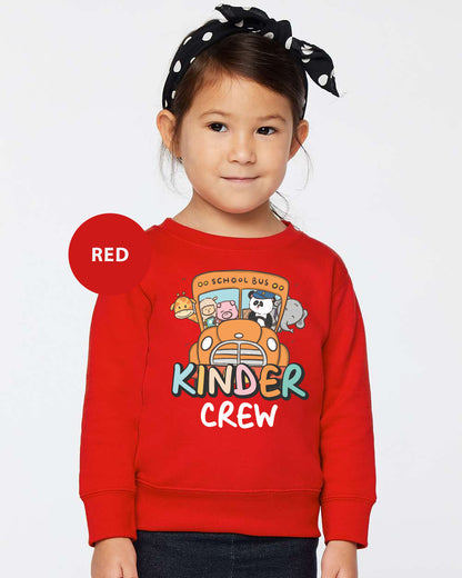 a little girl wearing a red sweater with a bus on it