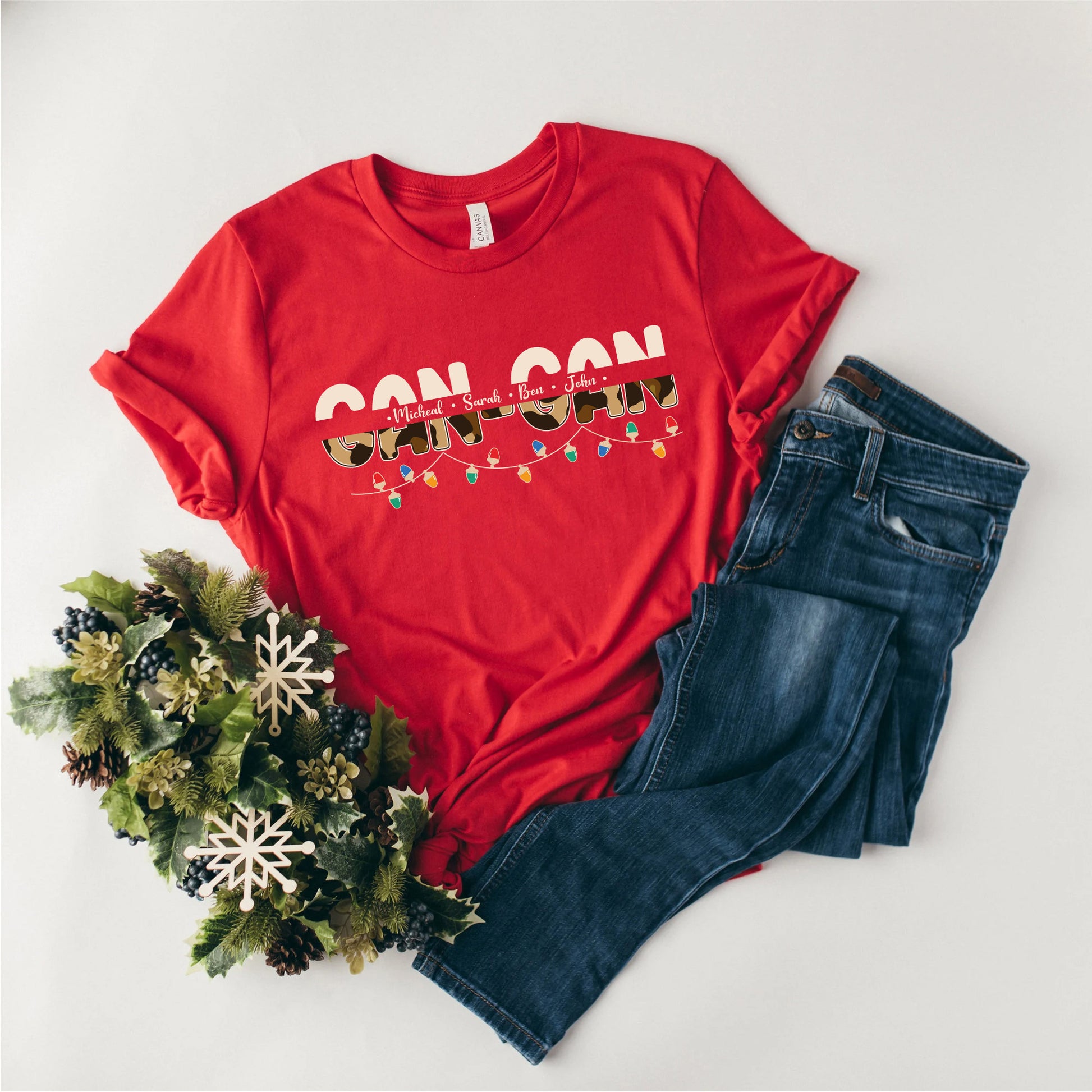 A red t-shirt with the text "CON CON" printed on it, along with a pair of blue jeans and a wreath of pine cones.