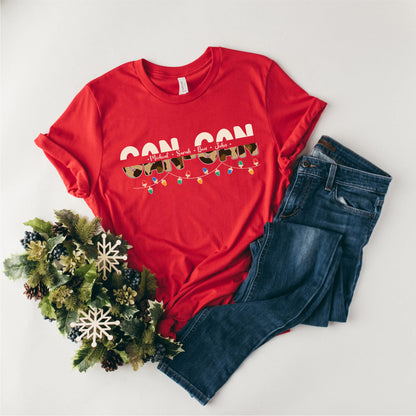 A red t-shirt with the text "CON CON" printed on it, along with a pair of blue jeans and a wreath of pine cones.