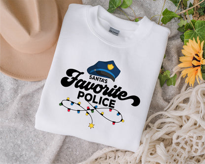 A white t-shirt with a graphic design and text, along with a hat and some greenery, is displayed on a surface.