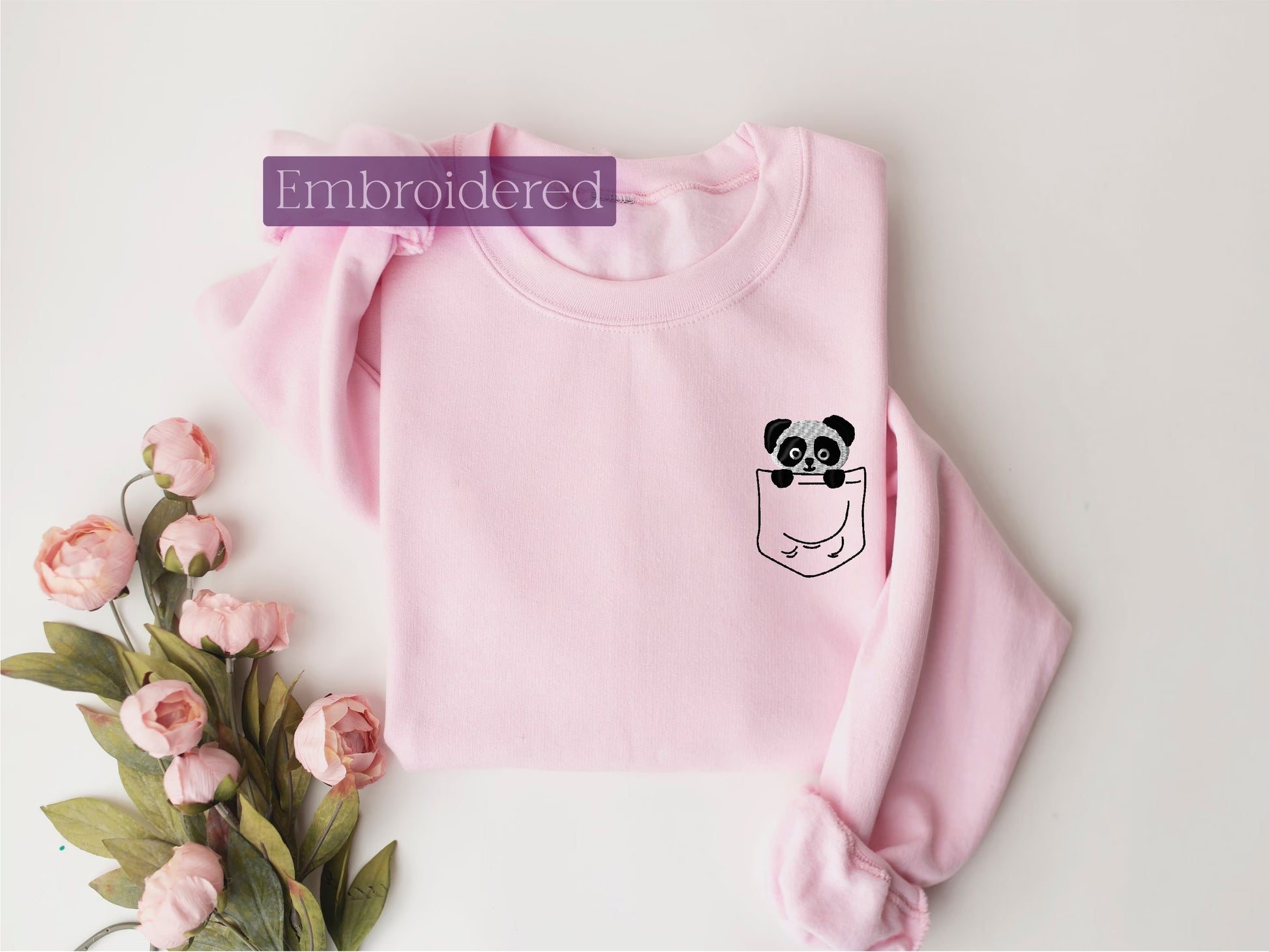 a pink sweater with a panda in a pocket