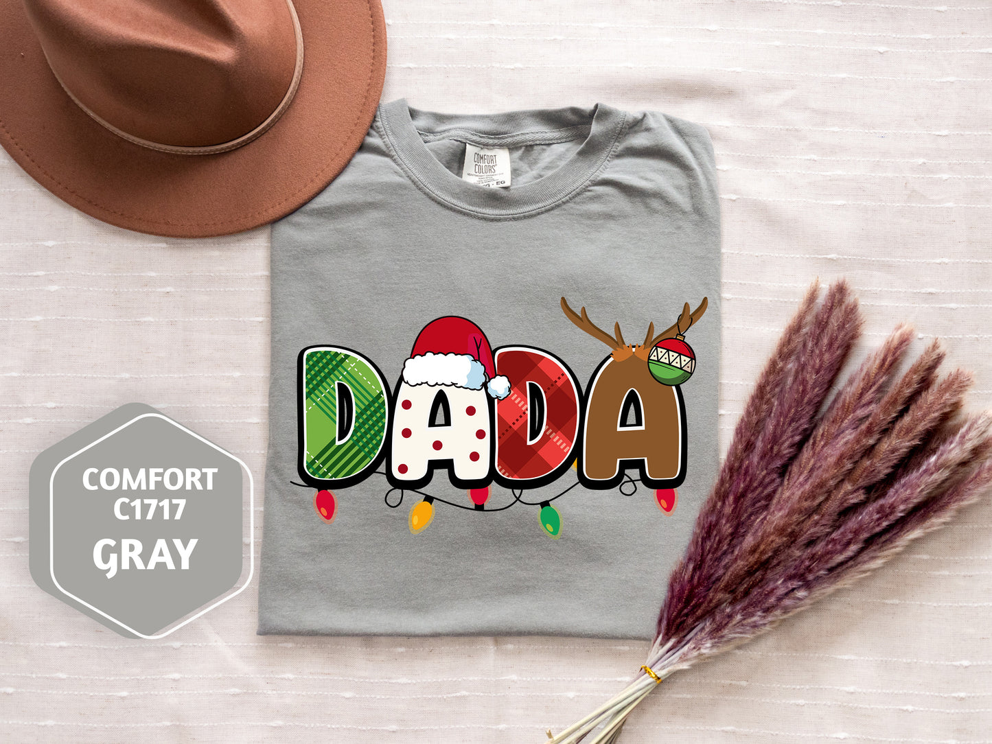 a gray t-shirt with a colorful design, a brown hat, and some decorative reindeer antlers, all placed on a white surface.