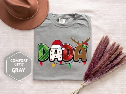 a gray t-shirt with a colorful design, a brown hat, and some decorative reindeer antlers, all placed on a white surface.
