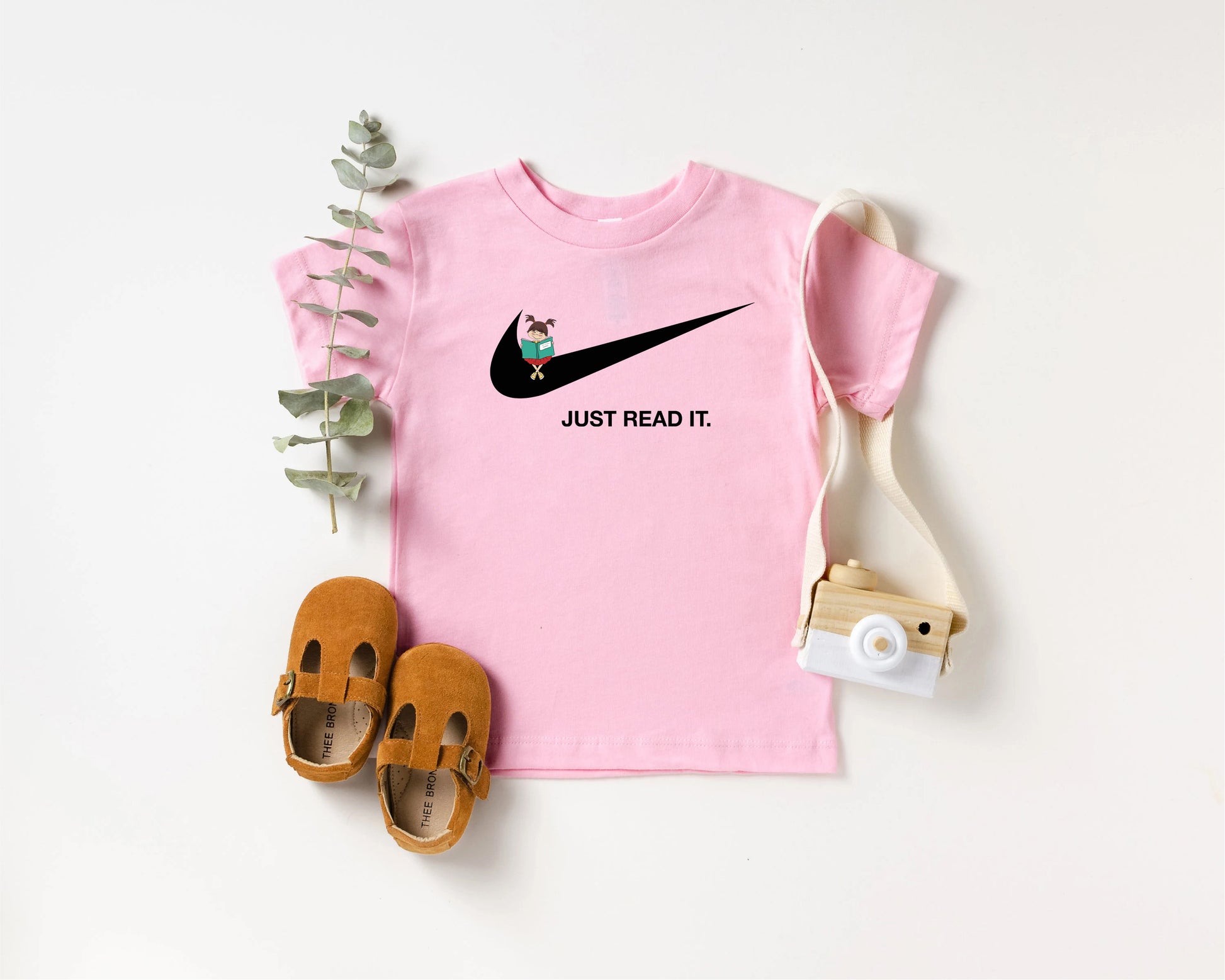 a pink shirt with a black nike logo and a pair of brown shoes