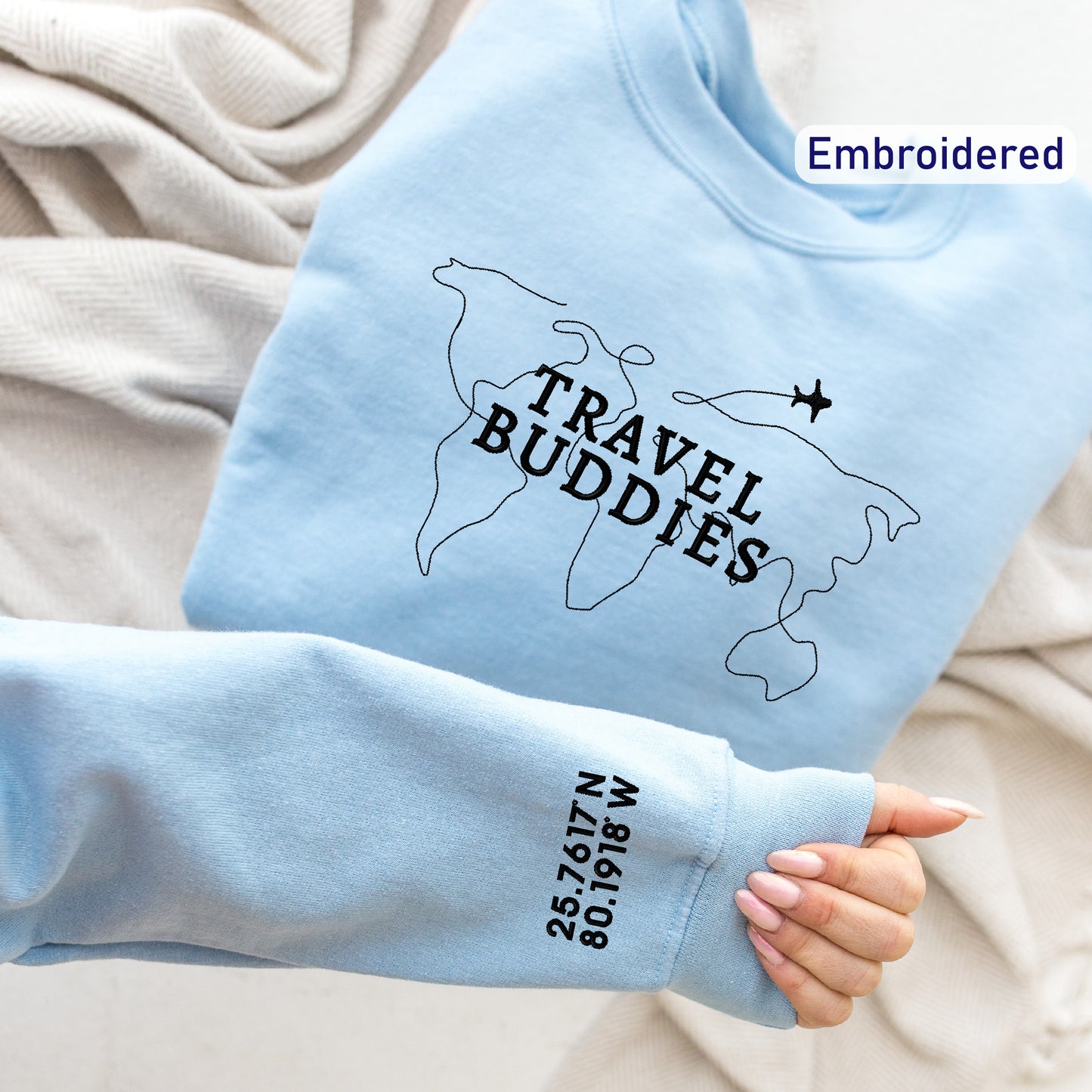 a person holding onto a blue sweatshirt with the words travel buddies on it