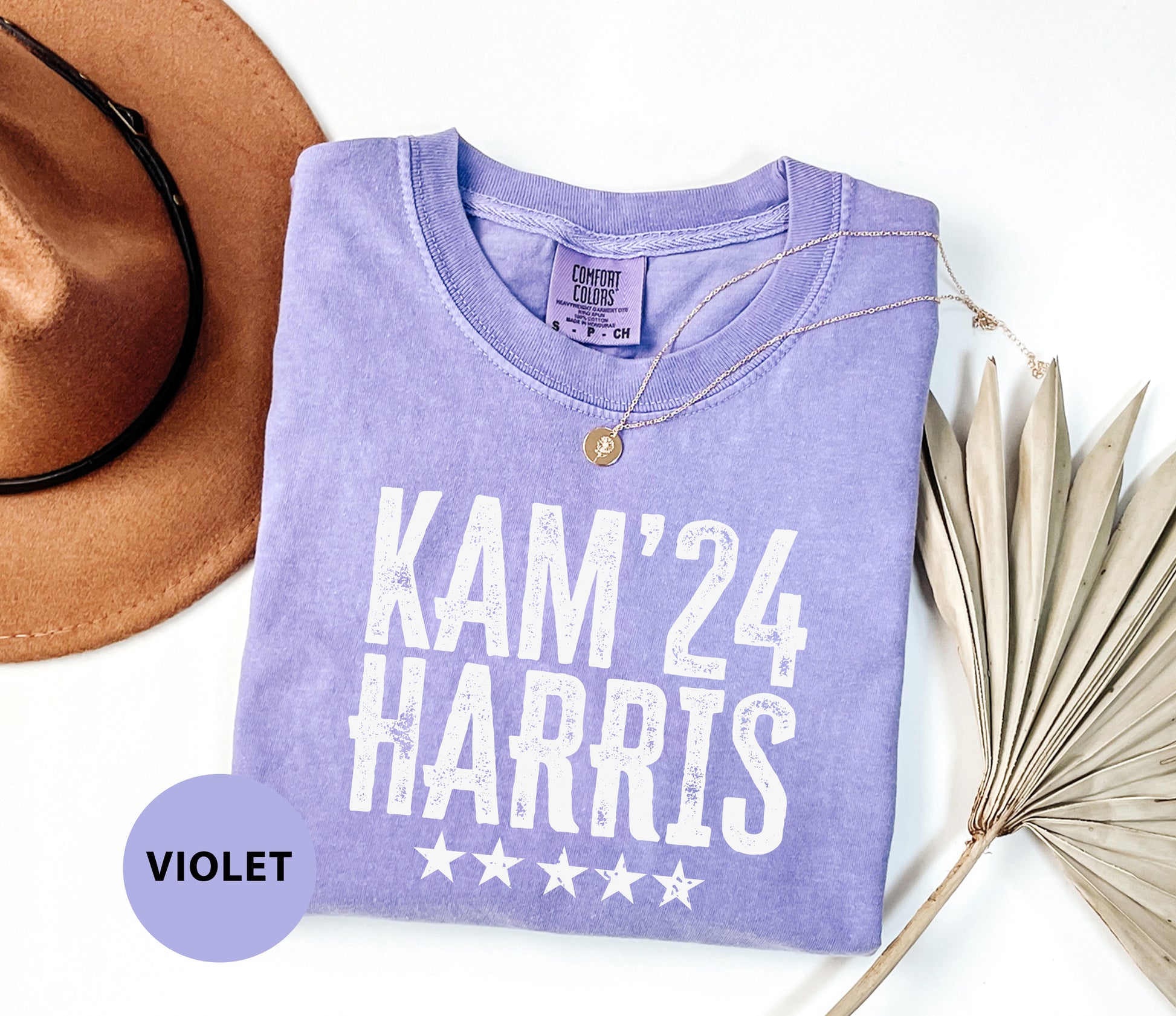 a purple shirt that says kam'24 harris next to a hat