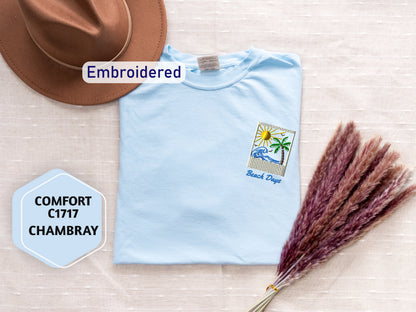 a light blue t-shirt with a beach-themed embroidered design, a brown hat, and a bunch of purple flowers, all laid out on a beige background.
