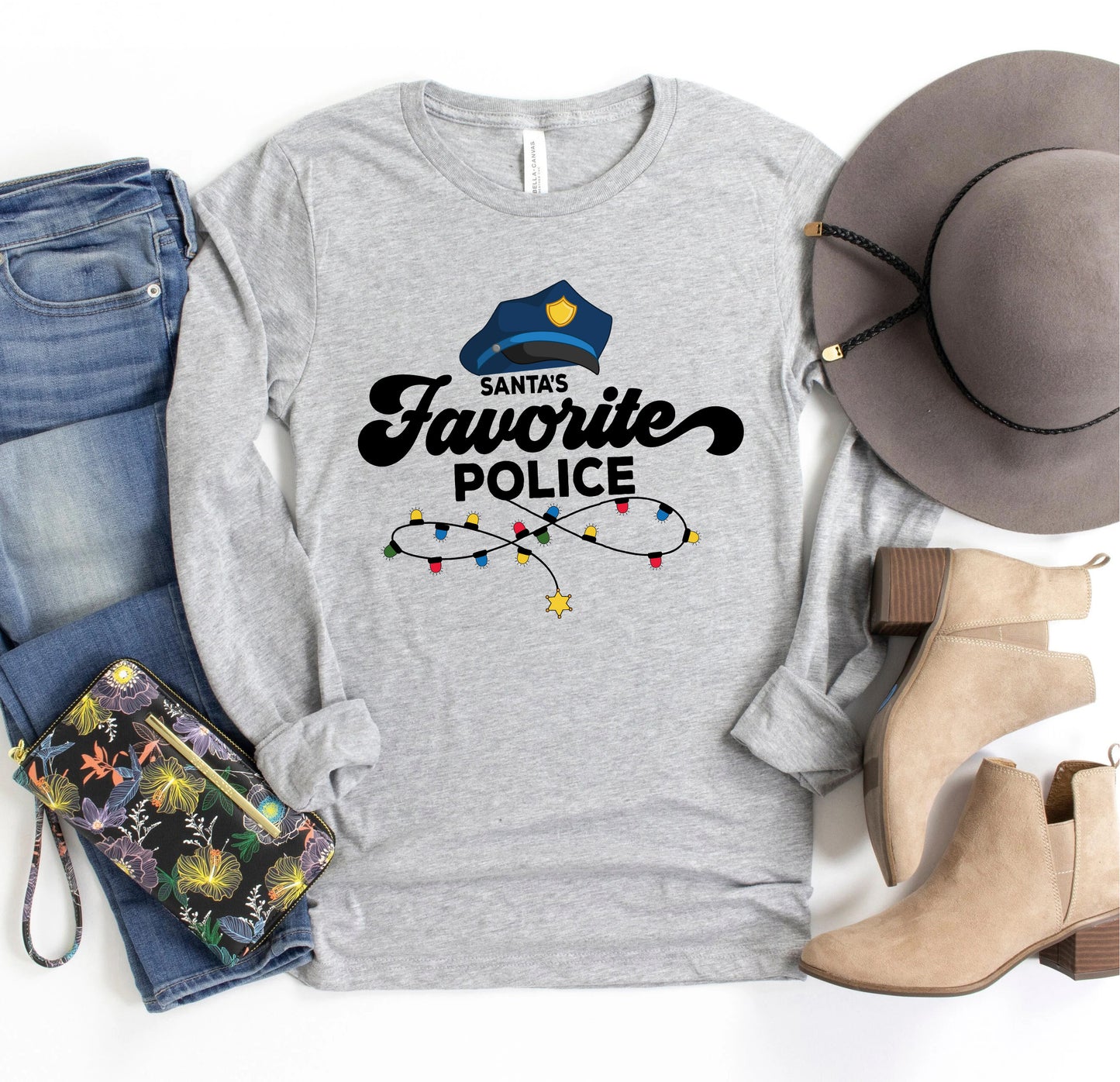 A gray long-sleeved t-shirt with a Santa hat and Christmas lights printed on it, along with a pair of jeans, a hat, and a pair of boots.