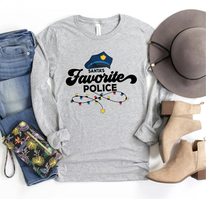 A gray long-sleeved t-shirt with a Santa hat and Christmas lights printed on it, along with a pair of jeans, a hat, and a pair of boots.