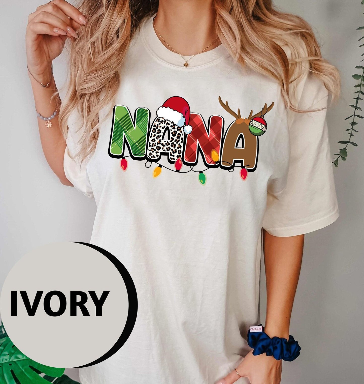 A woman wearing a white t-shirt with the word "NANA" printed on it, along with a Santa hat and Christmas lights.