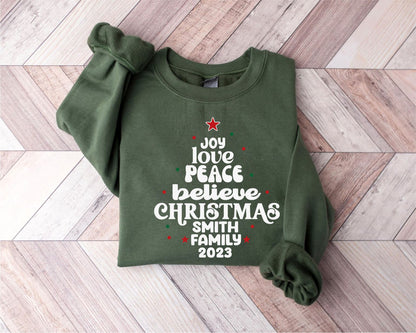 A green sweatshirt with a Christmas-themed design printed on it, laid out on a wooden surface.