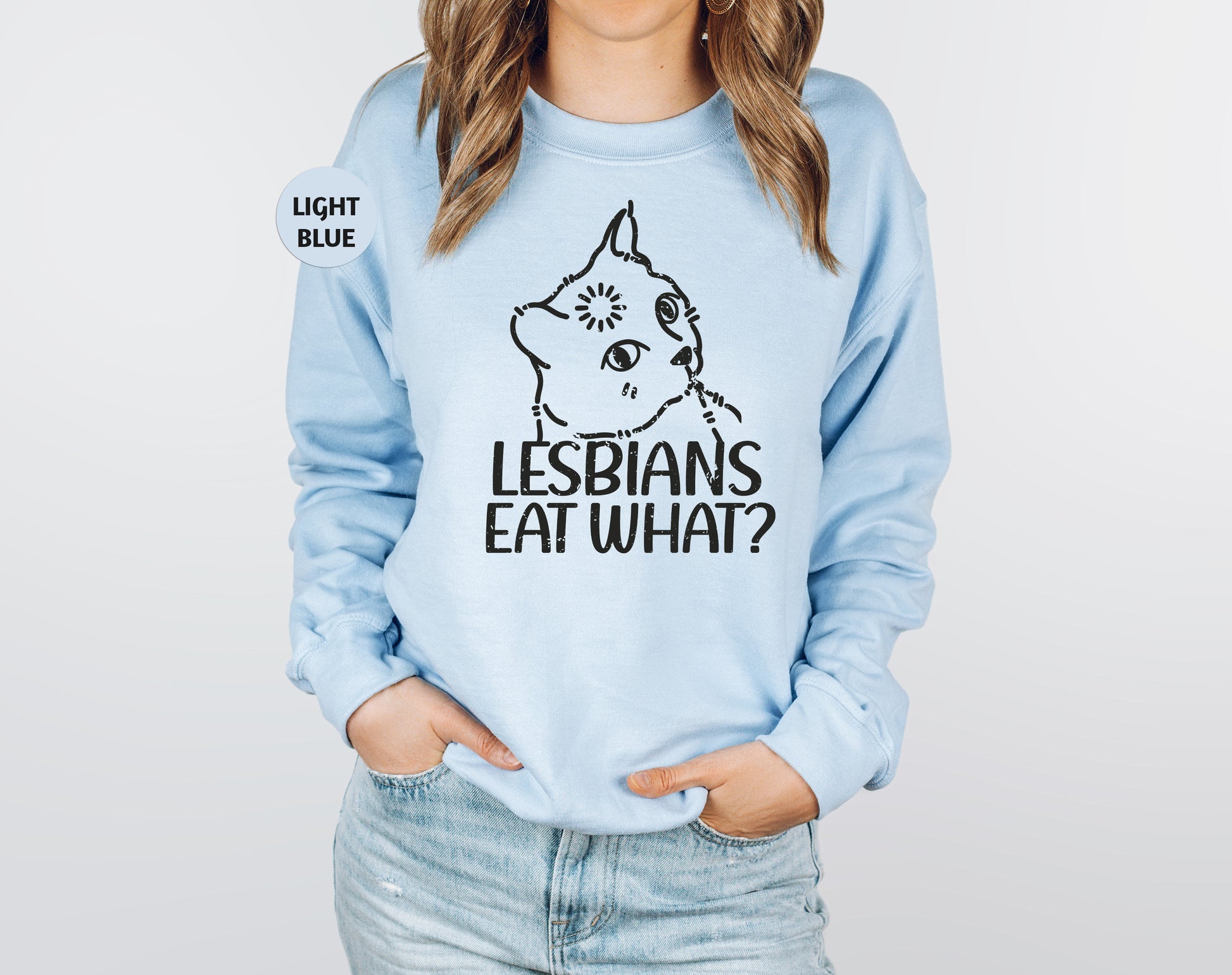 a woman wearing a light blue sweatshirt with the words lesbians eat what? on