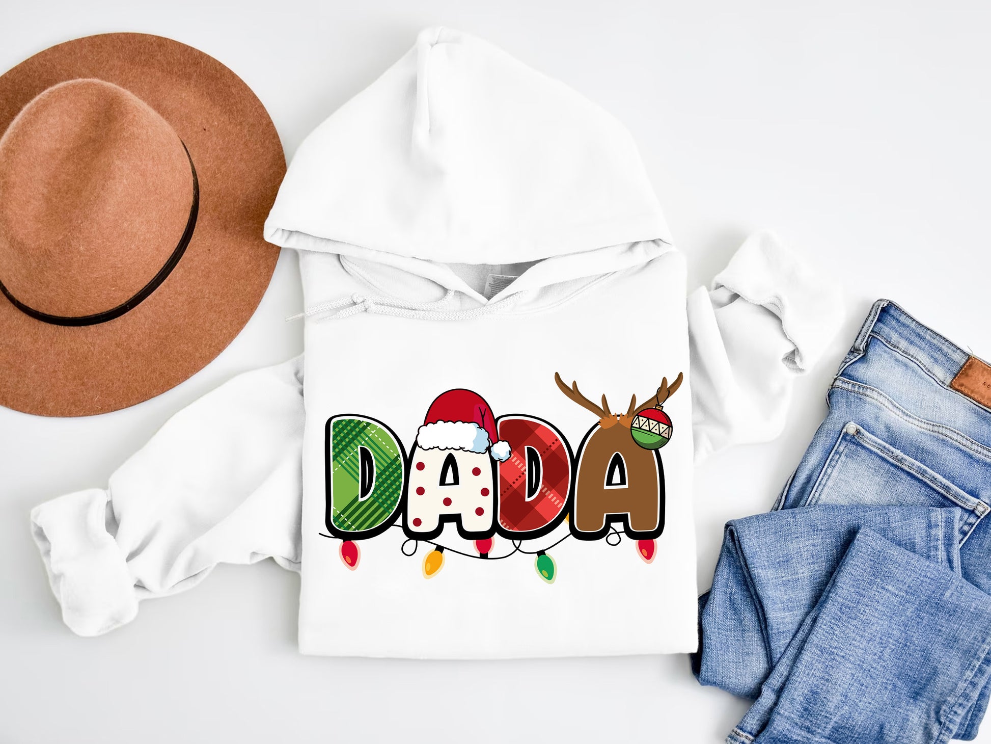 A white hoodie with the word "DADA" printed on it, along with a brown hat and a pair of jeans, are laid out on a white surface.