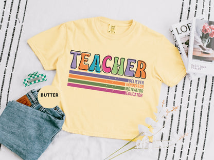 a t - shirt with the words teacher on it next to a pair of jeans