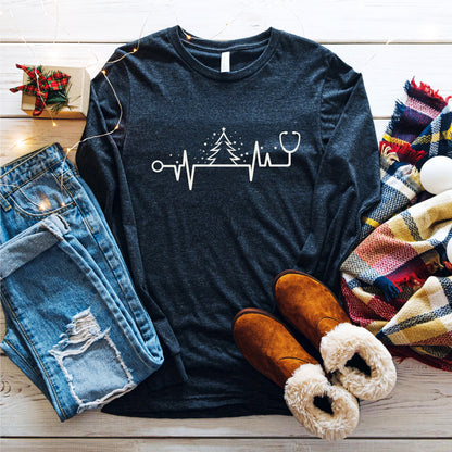 A casual outfit consisting of a long-sleeved black t-shirt with a white line graphic, distressed blue jeans, brown boots, and a colorful plaid scarf is laid out on a wooden surface.