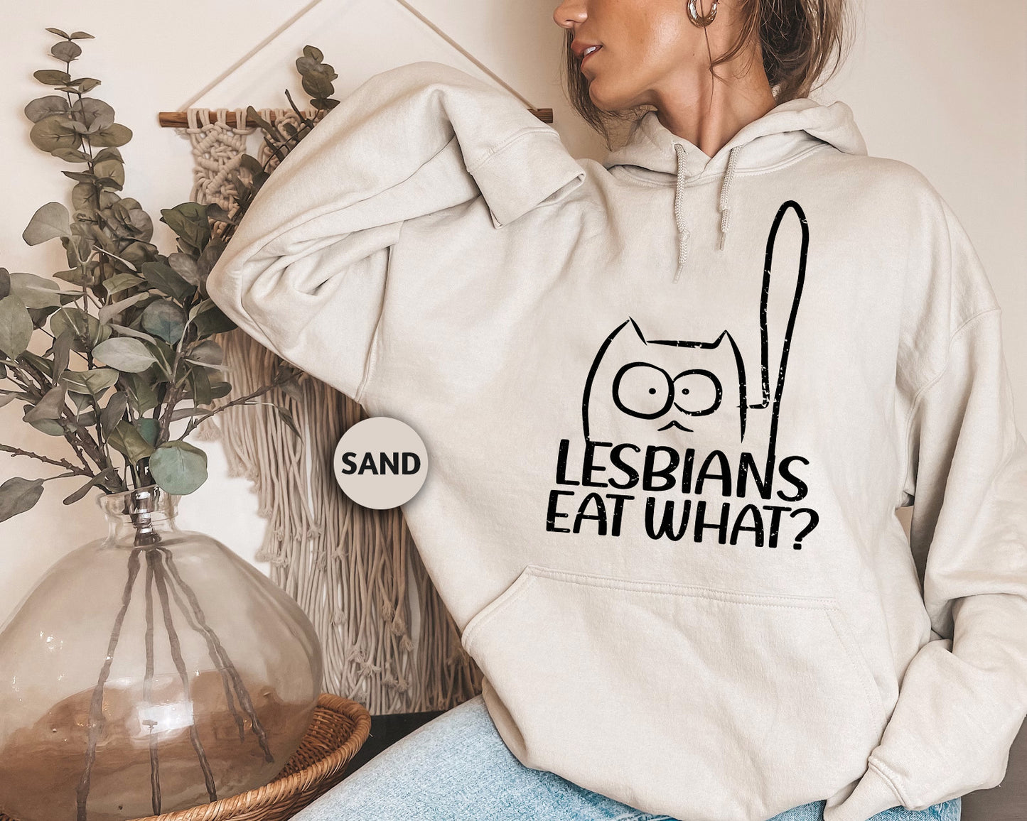 a woman wearing a sweatshirt with the words lesbians eat what? on it