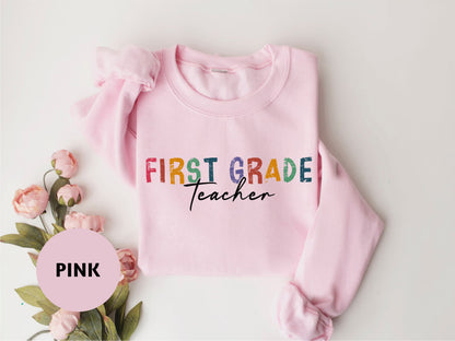 a pink sweatshirt with the words first grade teacher on it