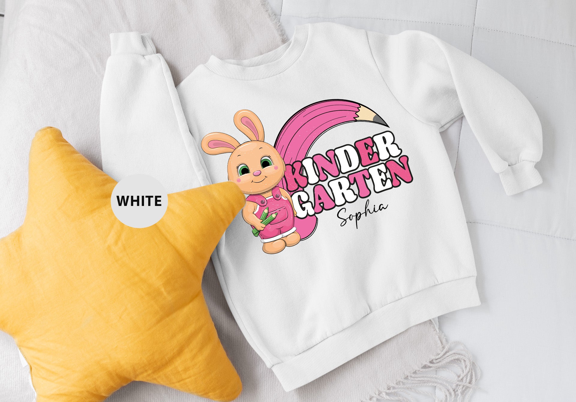 a white sweatshirt with a pink bunny on it next to a yellow star