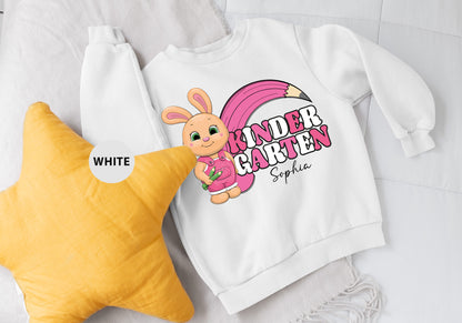 a white sweatshirt with a pink bunny on it next to a yellow star