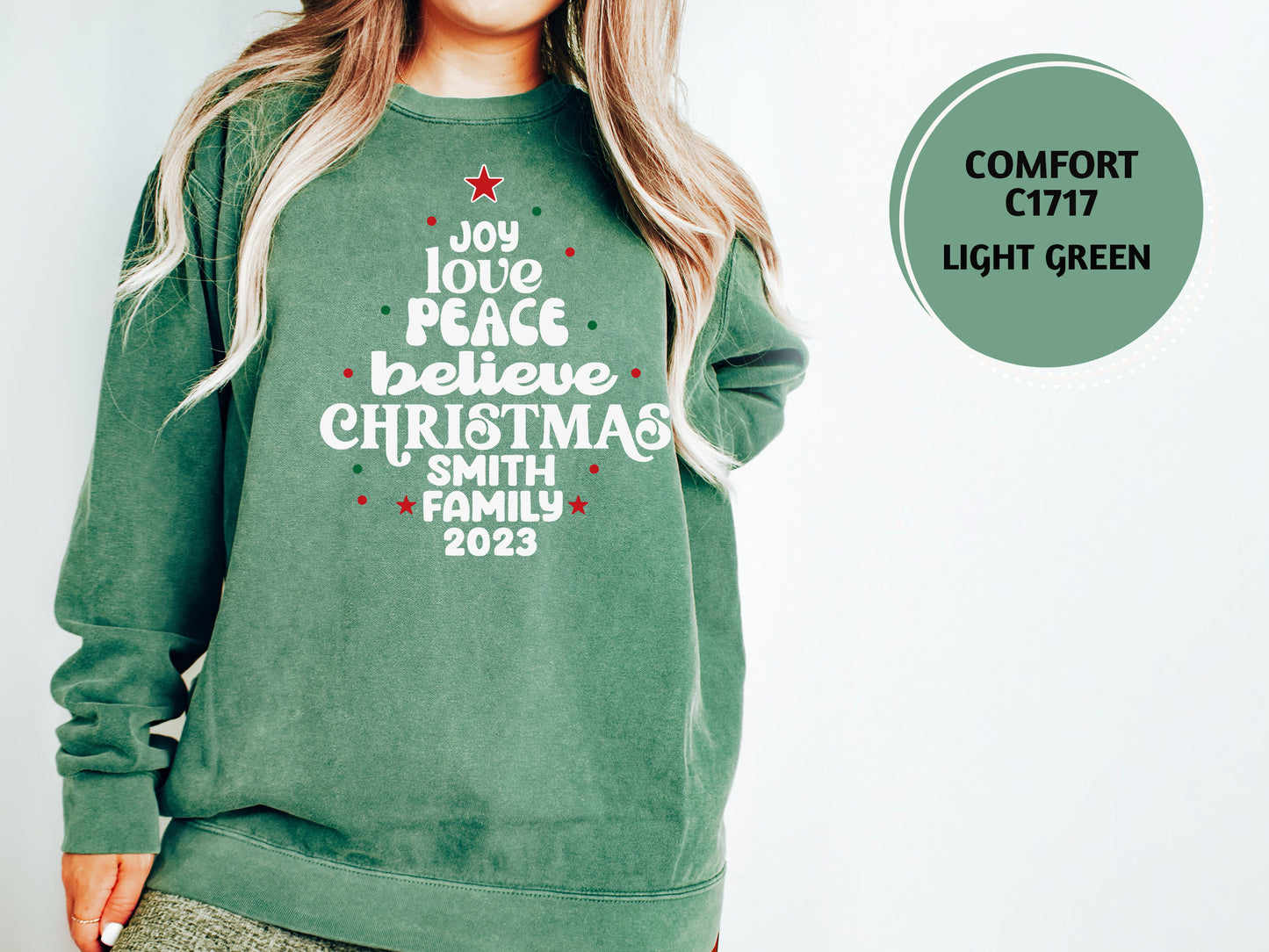 A woman wearing a green sweatshirt with a Christmas tree design and text printed on it.