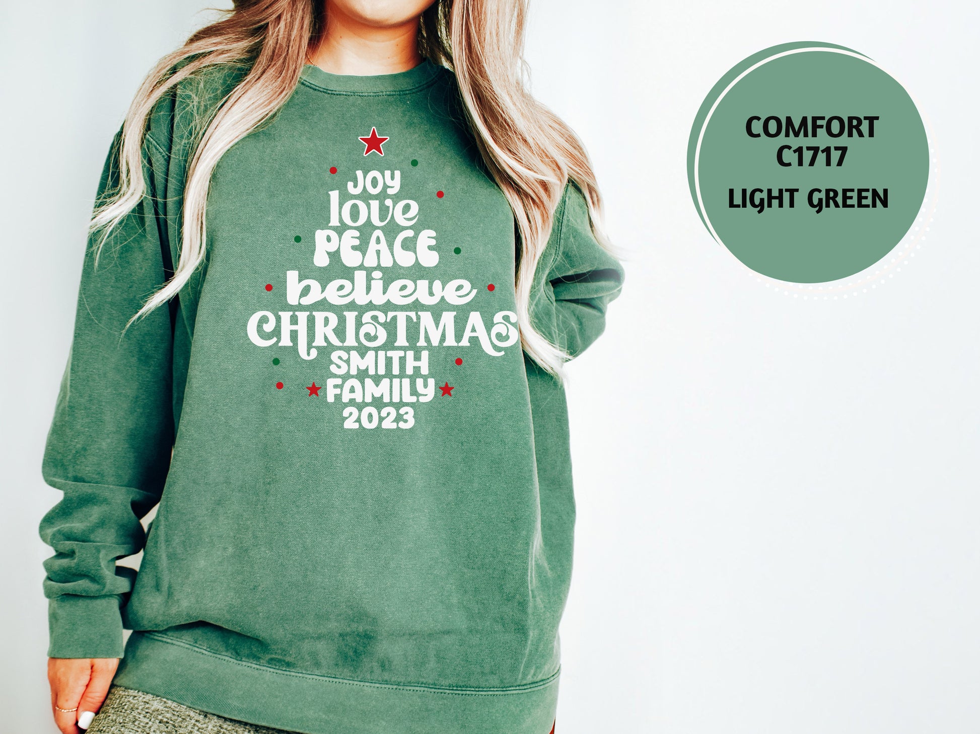 A woman wearing a green sweatshirt with a Christmas tree design and text printed on it.