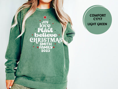 A woman wearing a green sweatshirt with a Christmas tree design and text printed on it.