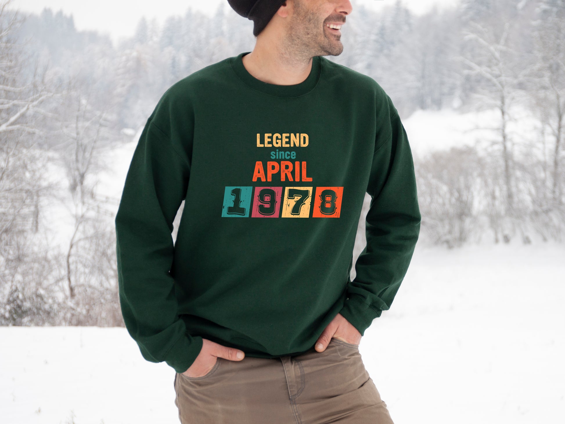 A man wearing a green sweatshirt with the text "LEGEND since APRIL 1978" printed on it, standing in a snowy outdoor setting.