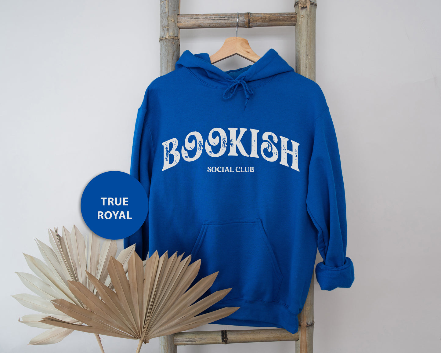 a blue bookish hoodie sitting on a chair next to a palm tree