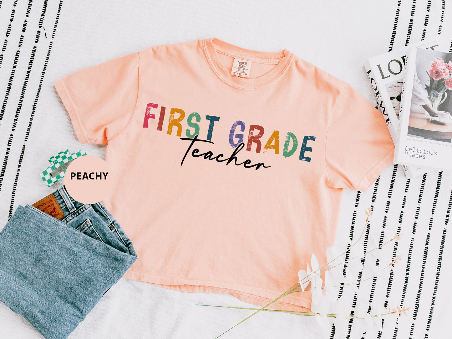 a pink shirt that says first grade teacher next to a pair of jeans