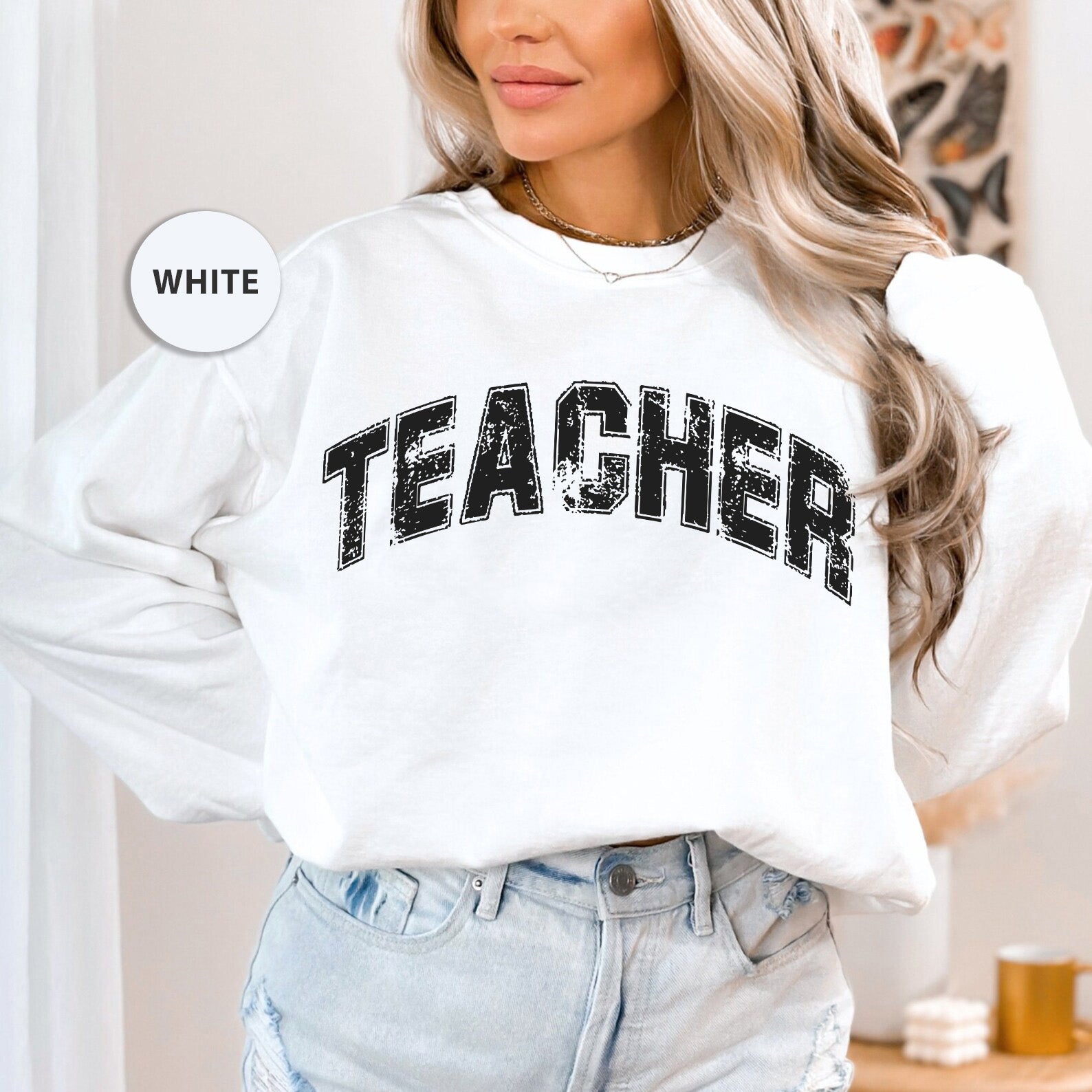 a woman wearing a white sweatshirt with the word teacher on it