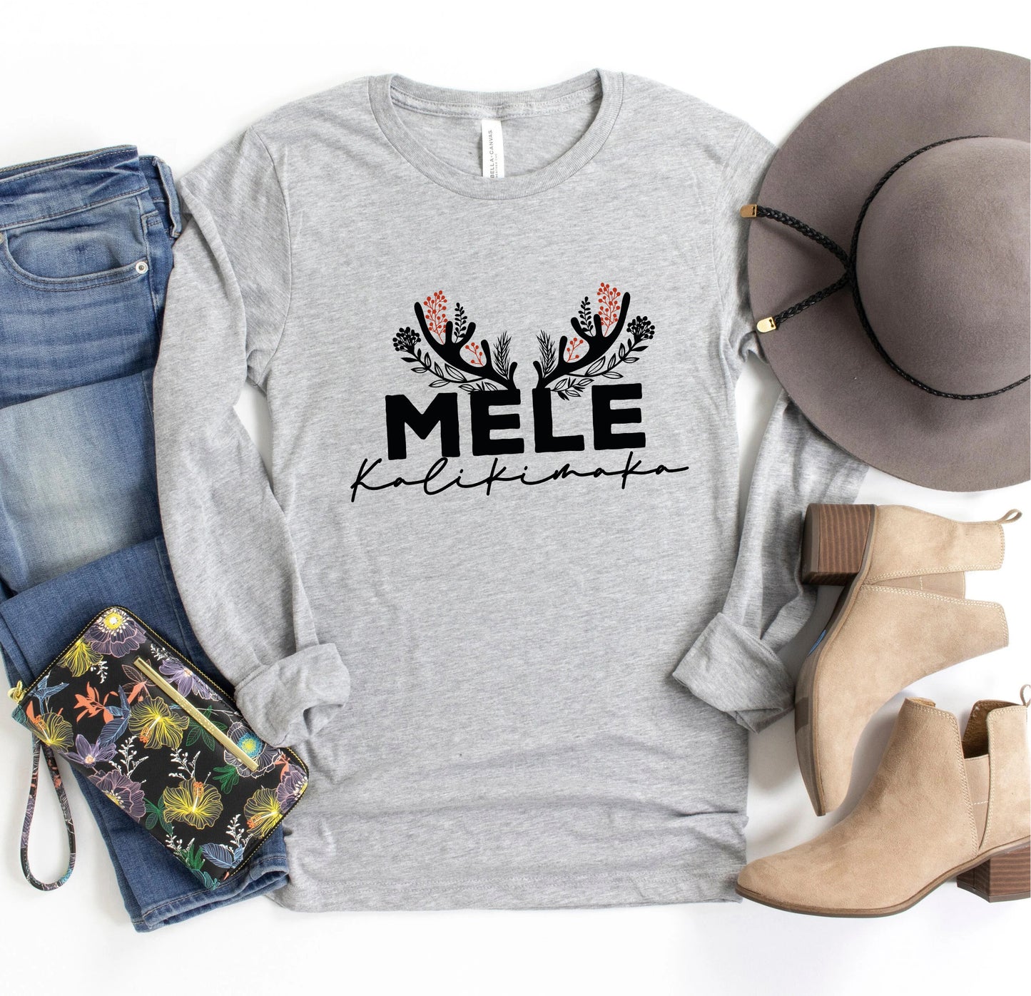 A casual outfit consisting of a gray long-sleeved shirt with a floral design, a pair of jeans, a hat, and beige ankle boots, along with a purse and a wallet.