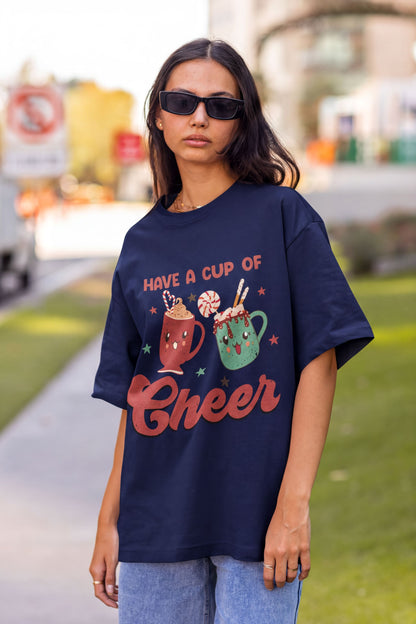A woman wearing a navy blue t-shirt with a graphic design of two colorful mugs and the text "Have a cup of cheer" printed on it.