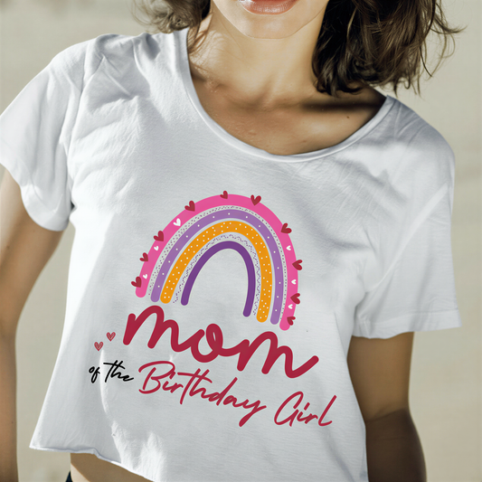 A woman wearing a white t-shirt with a colorful graphic design and text that says "Mom of the Birthday Girl".