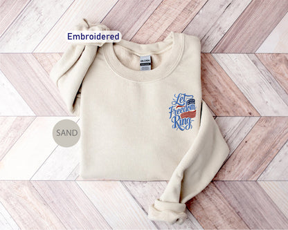 A beige sweater with an embroidered design on the front, placed on a wooden surface.