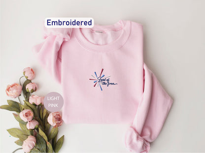 a pink sweatshirt with a floral embroidered design and the text "Light Pink" on it, along with a small floral arrangement on the side.