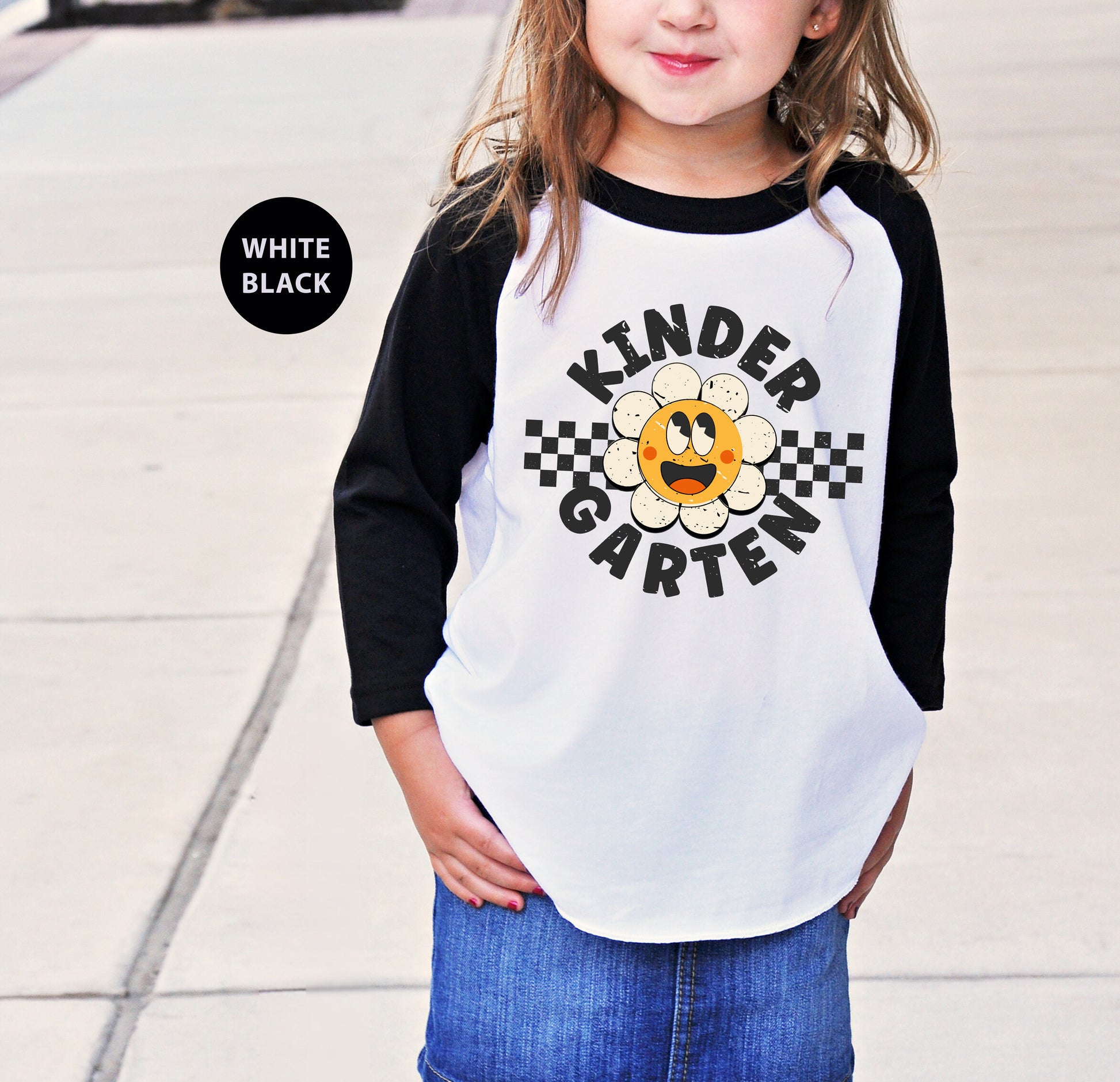 a little girl standing on a sidewalk wearing a white and black shirt