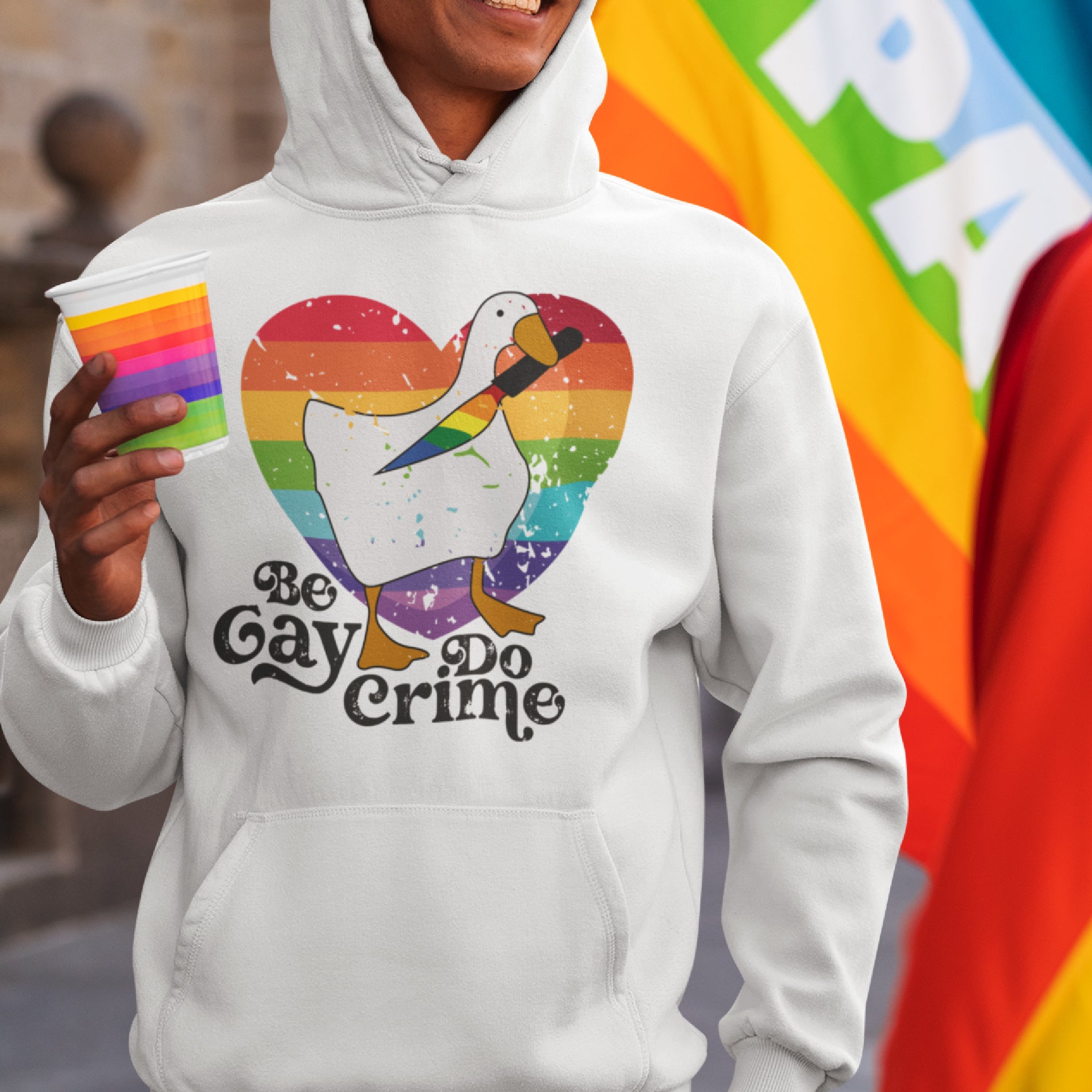 a man wearing a gay pride hoodie holding a rainbow card