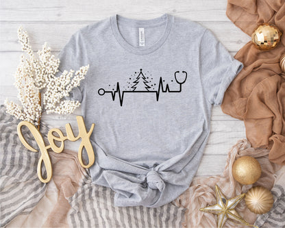 a gray t-shirt with a graphic design, a stethoscope, and some holiday-themed items such as a star, gold ornaments, and a garland.